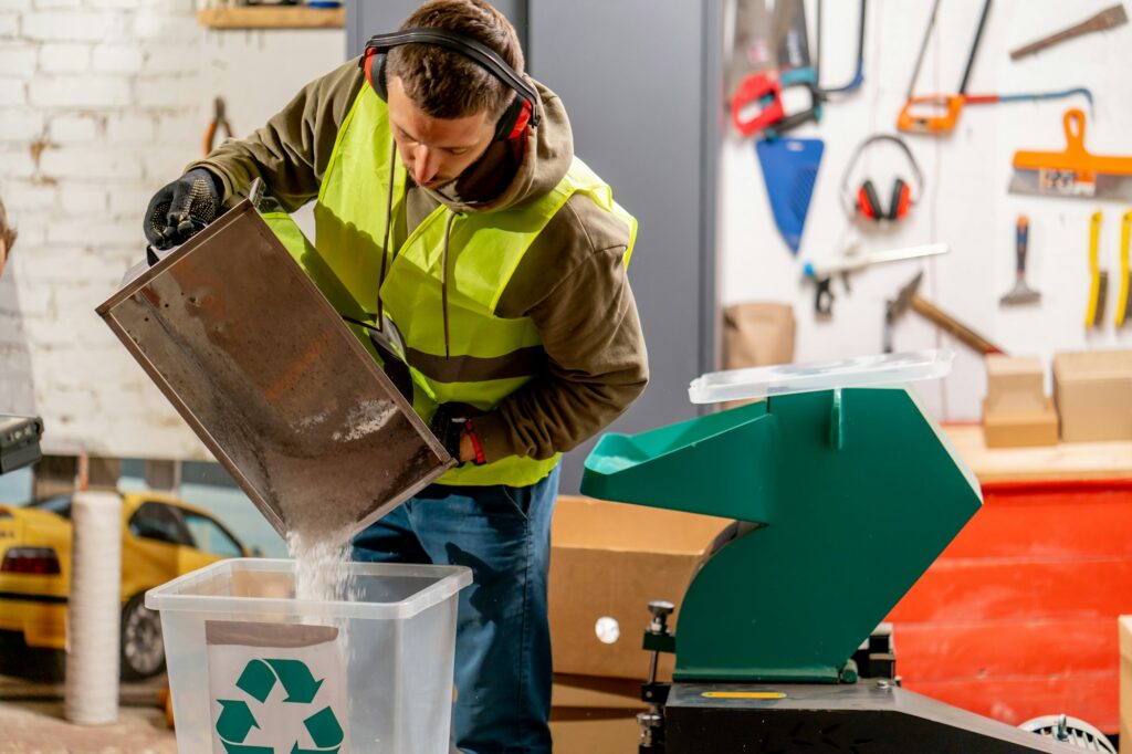 A waste recycling plant employee pours shredded plastic caps into container for recycling